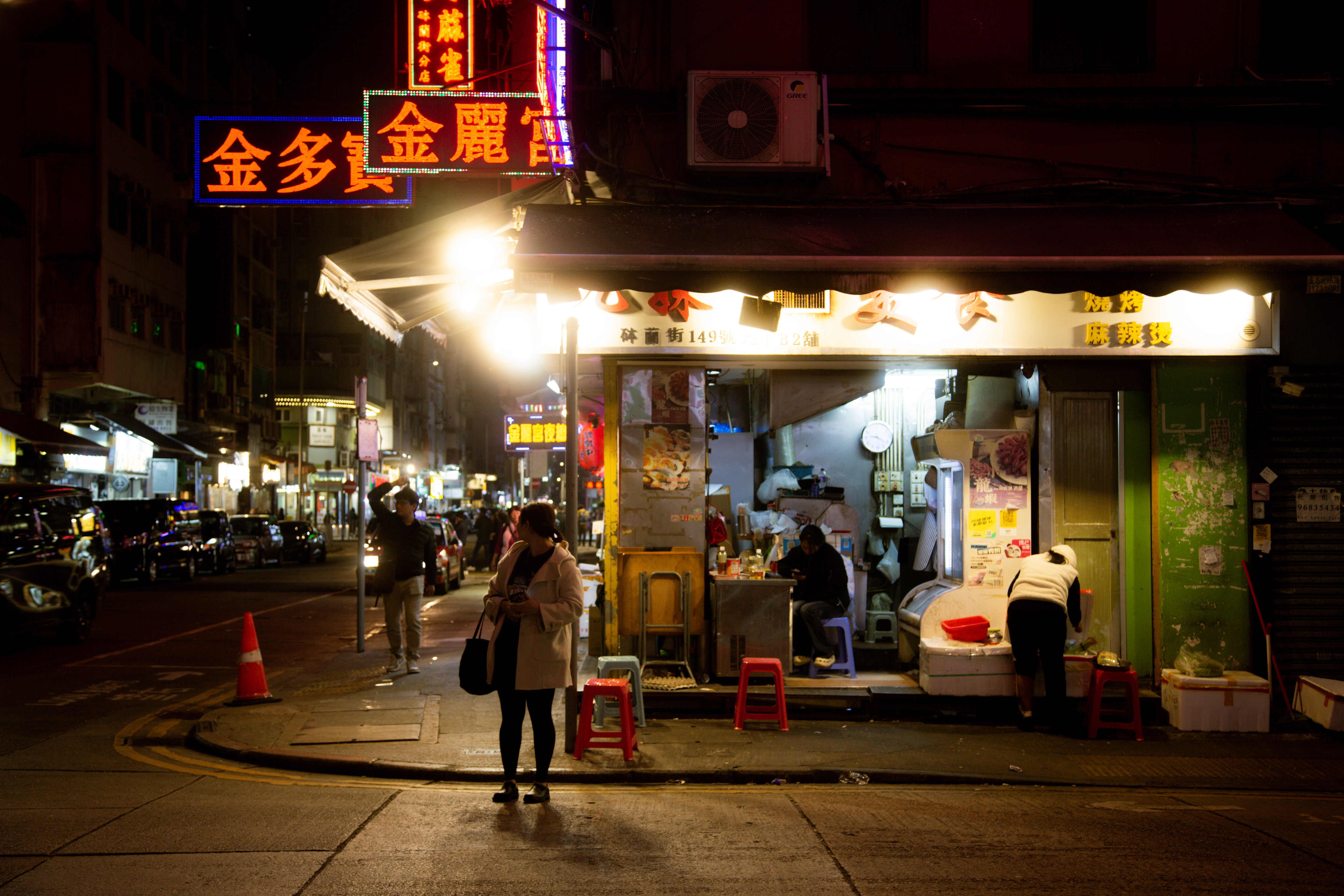 A woman waiting on a Hong Kong street at night